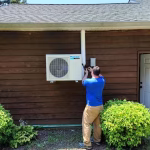 Roman HVAC technician performing an AC outdoor unit replacement and mini-split heat pump installation on a house wall.